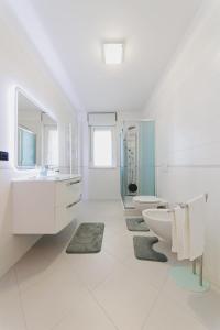 Baño blanco con 2 lavabos y 2 aseos en Swamyhome Aereoportobaripalese, en Bitonto