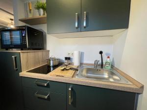 una cucina con lavandino e forno a microonde di Wolfsbutze - zentrales Motto Apartment a Verden