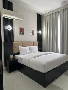 Al Zahra Hotel Apartments Ras Al Khaimah في رأس الخيمة: غرفة نوم بسرير كبير مع شراشف بيضاء