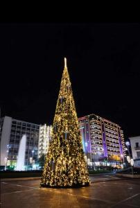 Un árbol de Navidad delante de una ciudad por la noche en Urban Rooms, en Atenas