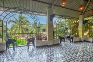 a room with chairs and a balcony with palm trees at Thomson Imperial Boutique G0A in Calangute