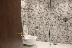 een badkamer met een toilet en een glazen douchedeur bij Hotel Madhuban in Silvassa