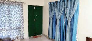 a pair of blue curtains and a green door at Malnad Bliss in Sringeri