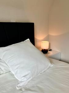 - un lit avec un oreiller blanc et une lampe dans l'établissement Airport Business Apartment, à Norderstedt