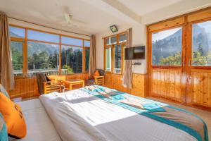 a bedroom with a bed and a tv and windows at Hide-in Old Manali in Manāli