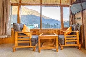 two chairs and a table in a room with a window at Hide-in Old Manali in Manāli