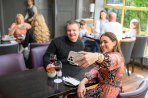 une femme assise à une table prenant une photo avec son téléphone portable dans l'établissement Newtown Park Hotel, à Wexford