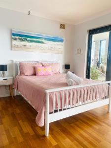 een slaapkamer met een bed met roze lakens en een raam bij Citadel Suite in Port Macquarie