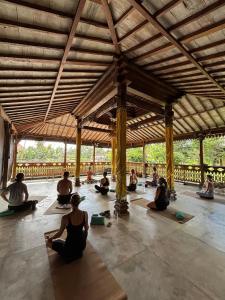 un grupo de personas sentadas en un pabellón haciendo yoga en Nunu Bali Eco Friendly Retreat, en Canggu