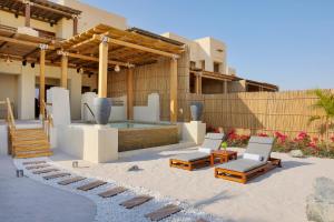 Al Wathba, a Luxury Collection Desert Resort & Spa, Abu Dhabi في أبوظبي: فناء مع مسبح وكراسي ومبنى