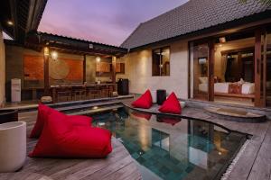 Zimmer mit einem Pool mit roten Kissen und einem Schlafzimmer in der Unterkunft Monique Ubud Villa in Ubud