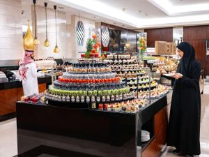 two women standing in front of a display of food at Swissotel Makkah in Makkah