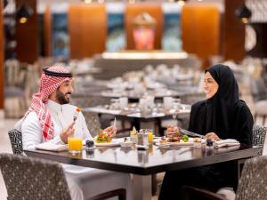 a man and woman sitting at a table eating food at Swissotel Makkah in Makkah