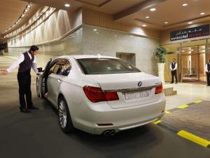 a man standing next to a white car in a mall at Swissotel Makkah in Makkah