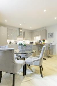 una cucina con tavolo in vetro, sedie e bancone di Elegant Epsom Flat in Period Building a Epsom