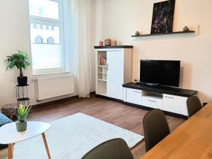 ein Wohnzimmer mit einem Flachbild-TV und einem Tisch in der Unterkunft Ferienwohnung Gemütliche Auszeit - Wallbox, nur 50m zum Hauptbahnhof, ruhig, Parterre, zentral, Hunde willkommen, Kinderausstattung vorhanden in Gotha