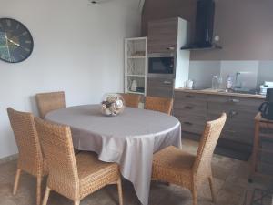 a kitchen with a table with chairs and a clock at Gîte Les Rainettes in Coye-la-Forêt