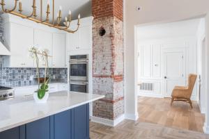 a kitchen with white cabinets and a brick wall at The Hen Houses in Wildwood