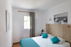 a bedroom with a bed with blue pillows and a window at Domaine Bocca di Feno in Bonifacio