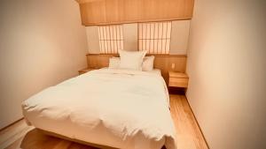 ein kleines Schlafzimmer mit einem weißen Bett und zwei Fenstern in der Unterkunft THE KAKU Exclusive suite & Residence in Nara