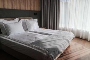 Una cama con sábanas blancas y almohadas en un dormitorio en Best Western Plus Lozenetz Hotel, en Sofía