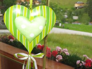 un adorno de corazón verde y blanco en una ventana con flores en Apartment Galtenberg, en Alpbach