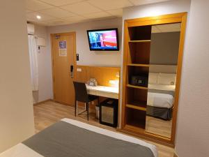 a hotel room with a bed and a desk and a tv at Mendez Nuñez Alicante in Alicante