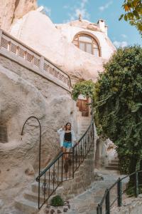 a woman sitting on the railing of a staircase in a house at Cappadocia Gamirasu Cave Hotel in Urgup