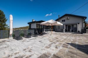 a patio with chairs and an umbrella in front of a house at Relax house MAROKIS in Karlovac