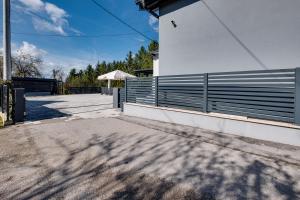 a white building with a fence and an umbrella at Relax house MAROKIS in Karlovac