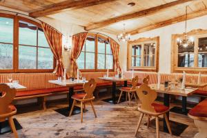 un restaurant avec des tables, des chaises et des fenêtres dans l'établissement Hotel Lammwirt, à Grossarl