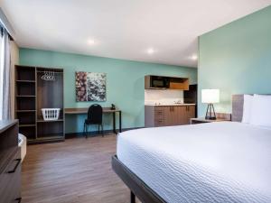 una camera con letto e scrivania e una cucina di ECHO Suites Extended Stay by Wyndham Indianapolis AmeriPlex a Indianapolis