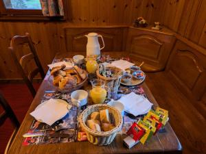 a table with a breakfast of bread and orange juice at La source in Sondernach