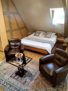 a bedroom with a bed and two leather chairs at Maison Rebleuthof Sauna & Fitness in Riquewihr