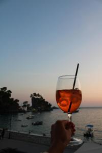 eine Person, die ein Glas Wein vor dem Meer hält in der Unterkunft PARALIA Stoudios in Parga