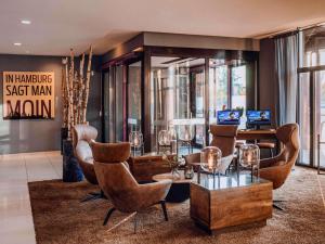 a lobby with chairs and a table with glasses on it at Mercure Hotel Hamburg City in Hamburg