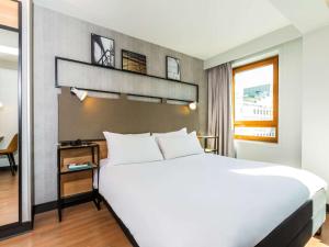 Un dormitorio con una gran cama blanca y una ventana en ibis Paris Bastille Opera, en París