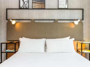 1 dormitorio con 1 cama grande con almohadas blancas en ibis Paris Bastille Opera, en París