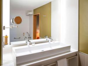 bagno con lavandino bianco e specchio di Hotel Mercure Porto Gaia a Vila Nova de Gaia