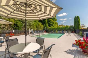 een tafel met een parasol naast een zwembad bij Best Western Plus Cold Spring in Plymouth