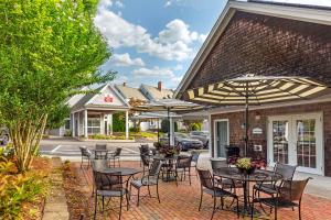 een patio met tafels en stoelen met parasols bij Best Western Plus Cold Spring in Plymouth