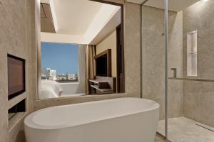 bagno con vasca e grande specchio di Sheraton Grand Bengaluru Whitefield Hotel & Convention Center a Bangalore