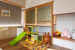 una sala de juegos para niños con un tobogán verde y juguetes en Yumenoi, en Himeji