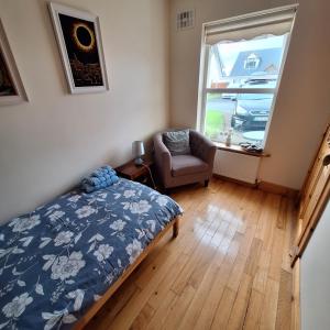 een slaapkamer met een bed, een stoel en een raam bij Lovely Single Room in Listowel Kerry in Listowel