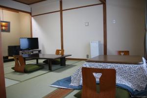 een woonkamer met een tafel en een televisie bij Miyajima Hotel New Kotobuki in Miyajima