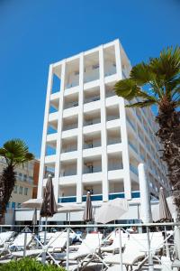 a large white building with chairs and umbrellas at Hotel Cavalieri Palace in Lido di Jesolo