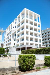 a large white building with bushes in front of it at Hotel Cavalieri Palace in Lido di Jesolo