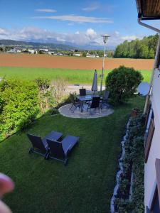 eine Terrasse mit einem Tisch, Stühlen und einem Feld in der Unterkunft Ferienwohnung-Hajek in Sankt Ruprecht an der Raab