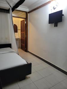 una camera con letto e TV a parete di Chel and Vade Cottages a Jinja