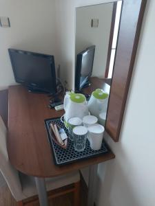 een bureau met een televisie en een tafel met kopjes bij Guest House Skalite in Sozopol